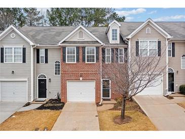 Three-unit townhome complex with brick and siding exteriors, featuring attached garages and landscaping at 438 Lantern Wood Dr, Scottdale, GA 30079