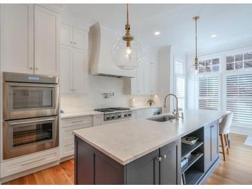 Modern kitchen featuring a large island, stainless steel appliances, and stylish pendant lighting at 235 Founders Mill Ct, Roswell, GA 30075