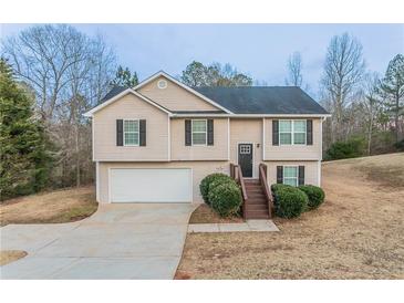 Split-level home with light siding, black shutters, a garage, and landscaped bushes near the front entrance at 100 Arthurs Ln, Covington, GA 30016