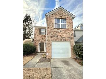 Brick townhouse with a white garage door and landscaping at 1635 River Main Ct, Lawrenceville, GA 30044