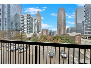 City skyline view from condo balcony with black metal railings overlooking parking in front of Atlanta skyscrapers on a sunny day at 1075 Peachtree Ne Walk # A421, Atlanta, GA 30309