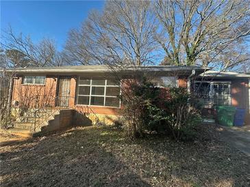 Quaint brick home featuring a well-manicured lawn, mature trees, and a welcoming front entrance at 2244 Alpha Dr, Decatur, GA 30032