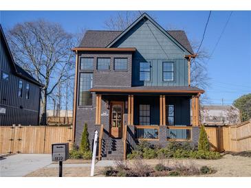 Two-story craftsman home with dark brick and teal siding, wood accents, and fenced yard at 1122 Nw Rice Nw St, Atlanta, GA 30318