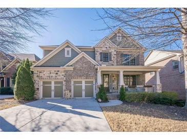 Two-story home with stone and siding accents, three-car garage, and front porch at 9994 Inisfree Dr, Johns Creek, GA 30022