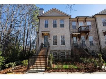 Brick front exterior of a charming townhome with a fenced yard and landscaping at 124 Everley Walk, Alpharetta, GA 30009