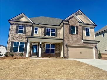 Charming two-story home featuring a stone and brick facade, complemented by a two-car garage at 407 Westmarch Cir, Loganville, GA 30052