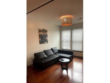 Living room with leather sectional sofa, wood floors, and large windows at 898 Oak St # 3423, Atlanta, GA 30310