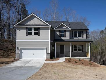 Two story home featuring gray siding, a two-car garage, covered porch, and professional landscaping at 250 Shawnee Trl, Dallas, GA 30157