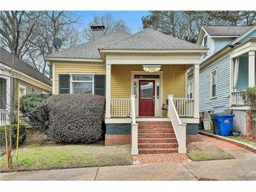 Charming yellow home featuring a welcoming front porch with swing and brick stairs at 725 Oakland Se Ave, Atlanta, GA 30315