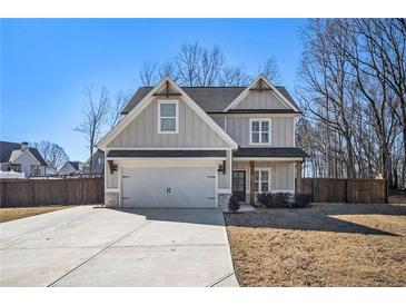 Two-story house with gray siding, a large driveway, and a fenced backyard at 61 Harmony Woods Ln, Dallas, GA 30157