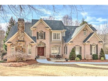 Stunning brick home with a stone chimney, manicured lawn, and a charming outdoor seating area at 4478 Outpost Ct, Roswell, GA 30075
