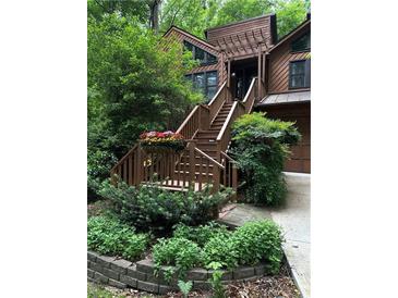 A beautiful entrance with wooden steps accented by flowering planters and verdant landscaping at 3457 Winter Wood Cv, Marietta, GA 30062