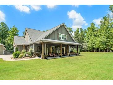 Charming home featuring a welcoming front porch with wood columns, lush lawn, and beautiful landscaping at 764 Little Vine Church Rd, Villa Rica, GA 30180