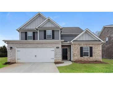 Charming two-story home featuring a mix of stone and brick, a two-car garage, and well-maintained lawn at 148 Oliver Dr, Locust Grove, GA 30248