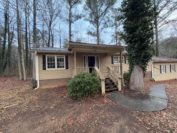 Tan house with black shutters, wooden steps, and landscaping at 6871 Lakeshore Dr, Douglasville, GA 30135