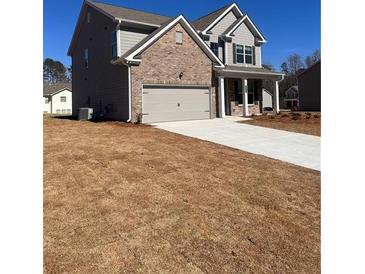 Charming two-story home with a brick and siding exterior, showcasing a spacious driveway and well-maintained lawn at 475 Paces Dr, Lithia Springs, GA 30122