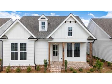 Charming white farmhouse-style home with brick-paved porch and manicured landscaping enhancing its curb appeal at 515 Cottage Creek Dr, Cumming, GA 30040
