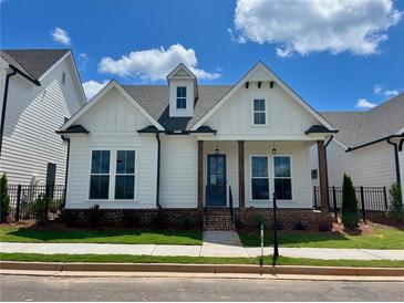 Charming white home featuring a landscaped yard, covered porch, and a combination of modern and traditional architectural elements at 515 Cottage Creek Dr, Cumming, GA 30040