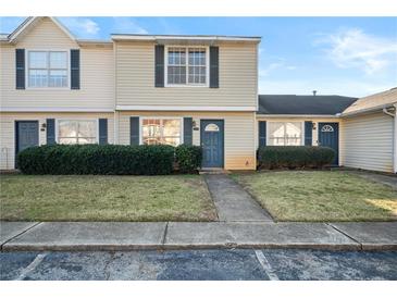 Tan siding townhouse with blue door, landscaping, and walkway at 319 Quincy Ave, Mcdonough, GA 30253