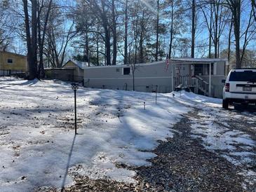 Mobile home on snow covered lot with trees and parked vehicle at 120 Valley Dr, Loganville, GA 30052