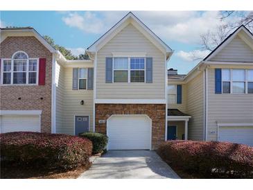 Charming two-story townhome featuring a one car garage, gray shutters, and manicured shrubs at 5665 Terremont Cir, Norcross, GA 30093