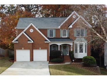 Brick two-story house with two-car garage, landscaping, and autumn trees at 912 Tanners Point Dr, Lawrenceville, GA 30044