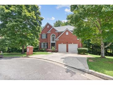 Brick two-story house with a two-car garage and landscaped lawn at 6519 Cheval Ct, Stone Mountain, GA 30087