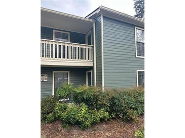 View of the exterior of a two-story condo building with lush landscaping and a balcony at 2824 Vinings Central Se Dr # 146, Atlanta, GA 30339
