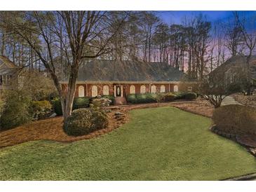 Charming single-story brick home featuring a lush front yard with mature trees and well-maintained landscaping at 10575 Stonefield Lndg, Johns Creek, GA 30097