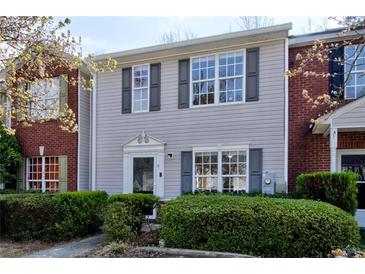 Charming townhome featuring neutral siding, complemented by dark shutters and mature landscaping at 2878 Norfair Loop, Lithonia, GA 30038
