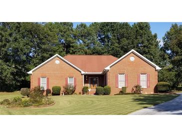 Charming brick home featuring a manicured lawn, symmetrical shrubbery, and tasteful landscaping at 2509 Fairweather Ct, Conyers, GA 30013