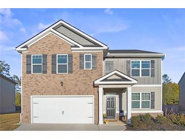 Two-story brick home with gray siding, a white garage door, and landscaping at 1508 Denver Way, Locust Grove, GA 30248