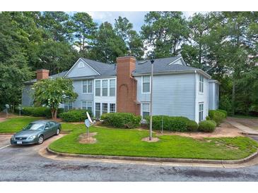 Gray siding condo building with brick accents, surrounded by lush green landscaping at 4321 Orchard Park Ct, Stone Mountain, GA 30083