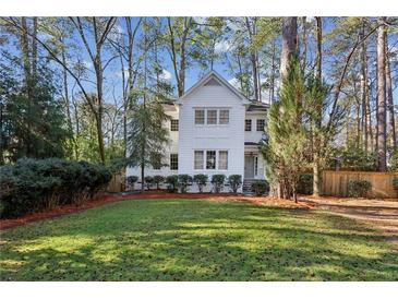 Charming white two-story house with well-manicured lawn and mature trees at 2460 Oldfield Rd, Atlanta, GA 30327