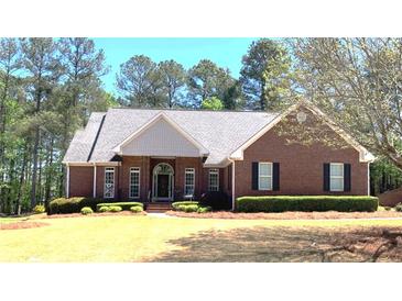 Beautiful brick home featuring a well-manicured lawn and a classic design with dark shutters and arched entry at 517 Mary Margaret Walk, Loganville, GA 30052