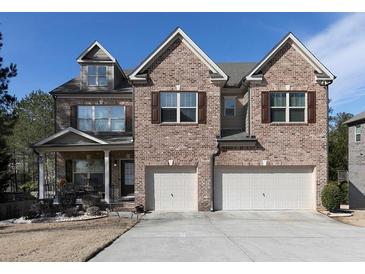 Charming brick home featuring a two-car garage and inviting front porch on a sunny day at 4417 Green Pastures Way, Ellenwood, GA 30294