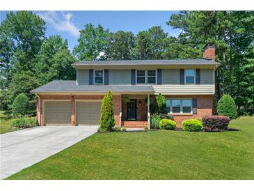 Charming two-story brick home with a manicured lawn, mature trees, and an attached two-car garage at 647 Shannon Green Cir, Mableton, GA 30126
