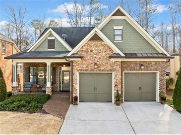 Charming home with brick and stone accents, covered porch, two-car garage, and landscaped front yard at 1545 Camden Cove Dr, Cumming, GA 30040
