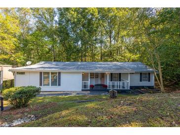 Charming single-story home with white siding, a covered porch, and a lush, wooded surroundings at 1355 Woodland Sw Dr, Oxford, GA 30054