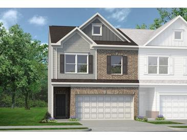 Two-story townhome with gray and brick exterior, two-car garage, and landscaping at 24 Jacobs Farm Ln # 12, Lawrenceville, GA 30045