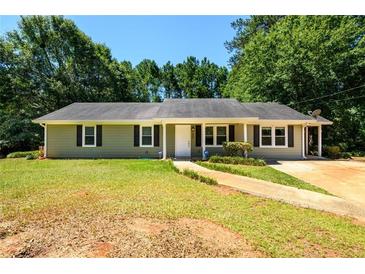 Ranch style home with green siding, landscaped yard, and driveway at 780 Navajo Trl, Covington, GA 30016