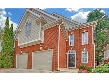 Two-story red brick home featuring a two car garage, arched windows and door, and manicured landscaping at 1125 Blackshear Dr, Decatur, GA 30033
