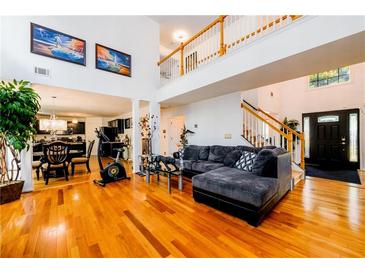 Spacious living room with hardwood floors, large windows, and a view of the kitchen and staircase at 1045 Paper Creek Dr, Lawrenceville, GA 30046