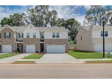 Two-story brick townhome with attached two-car garage and landscaped yard at 300 Navigator Ln, Mcdonough, GA 30253