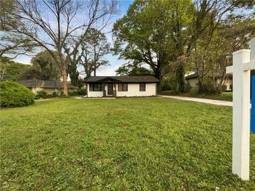 Charming one-story home featuring a well-manicured lawn and mature trees providing ample shade at 2704 Ellen Way, Decatur, GA 30032