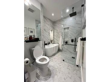 Modern bathroom with white marble walls, a luxurious soaking tub, and a glass-enclosed shower at 220 Renaissance Pkwy # 1203, Atlanta, GA 30308