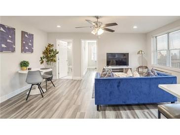 Bright living room with blue sofa, dining area, and hardwood floors at 300 Peachtree Ne St # 3B, Atlanta, GA 30308
