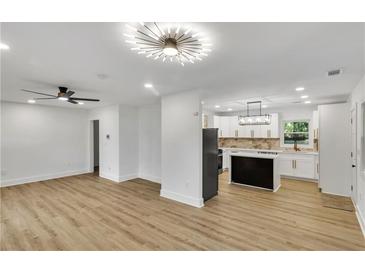 Open concept living room and kitchen with modern lighting fixtures and new hardwood floors at 2358 Tilson Rd, Decatur, GA 30032