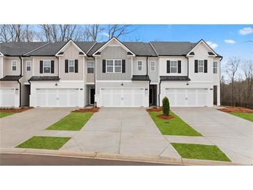 View of townhomes with modern exteriors, well-manicured lawns, driveways, and attached garages at 353 Sound Cir, Stockbridge, GA 30281