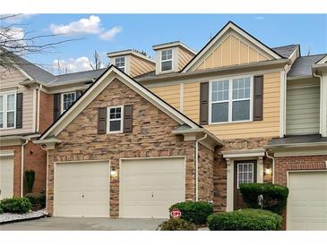 Two-story townhome with stone and siding exterior, three-car garage, and landscaping at 1693 Fair Oak Way, Mableton, GA 30126